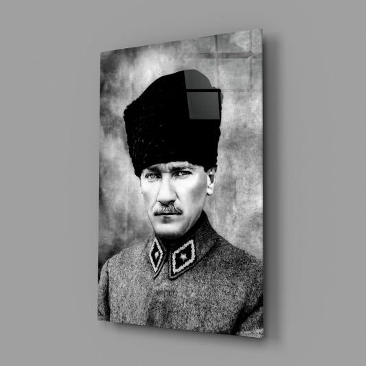 Black and white portrait photograph on glass panel showing a man in military uniform and traditional hat, displayed at an angle against gray background.
