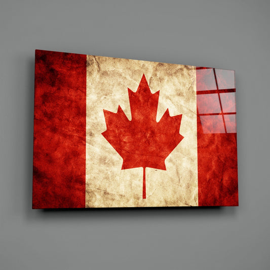 Angled front view of a glass wall art panel displaying a weathered Canadian flag with red maple leaf on cream and red background, mounted on gray wall.