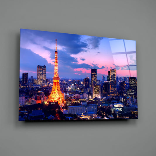 Illuminated Tokyo Tower at twilight dominates a cityscape printed on glass wall art mounted on gray wall.