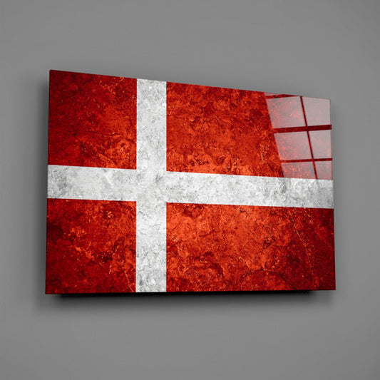 Danish flag glass wall art with mottled orange and white cross design mounted at angle against gray wall.
