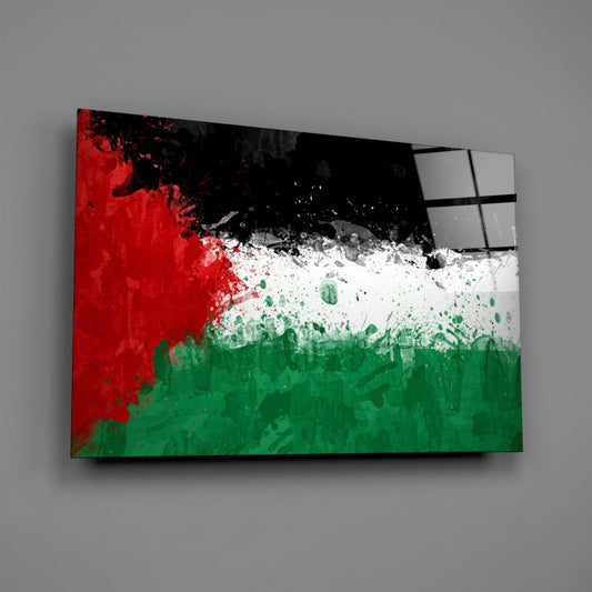 Angled view of a glass wall art panel displaying the Palestinian flag in watercolor splatter effect with red, white, and green colors against gray background.