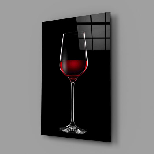 Glass wall art panel displaying a single red wine glass with deep crimson liquid against a black background, angled perspective view.