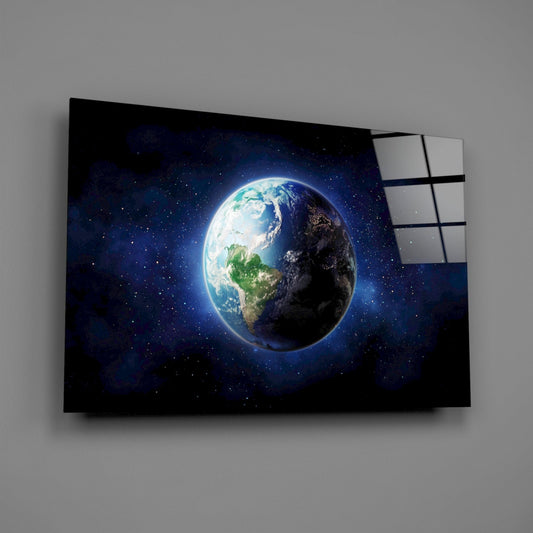 Angled view of glass wall art displaying illuminated Earth half in daylight, half in darkness, suspended in starry blue space against gray wall.