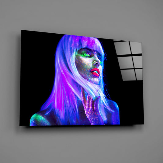 Angled view of glass wall art displaying a neon-lit portrait of a woman with vibrant purple hair, glowing green eyes, and red lips against black background.