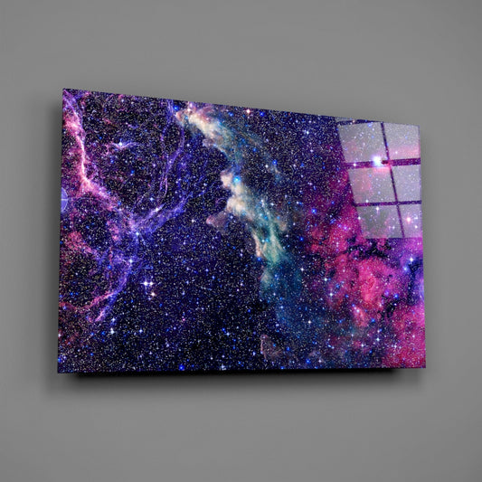 Angled perspective of glass wall art displaying purple, blue, and pink cosmic nebula clouds with starfield against gray background.