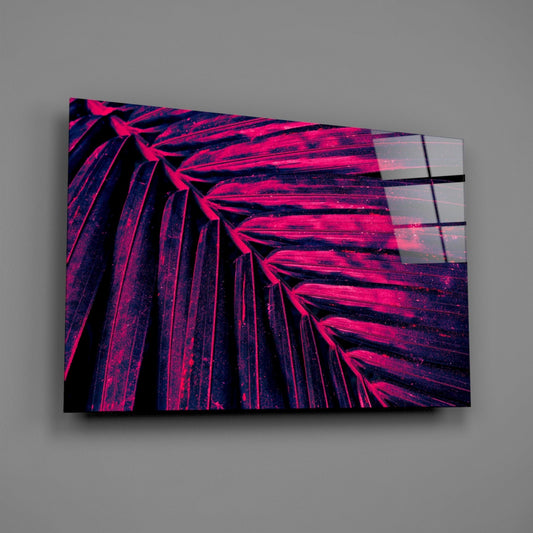 Angled perspective view of neon magenta and dark blue palm frond glass wall art against gray background.
