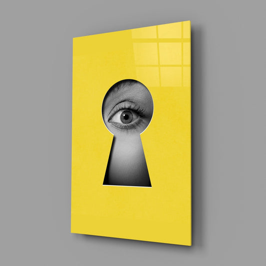 Angled view of yellow security glass wall art featuring a black and white eye peering through a keyhole cutout.