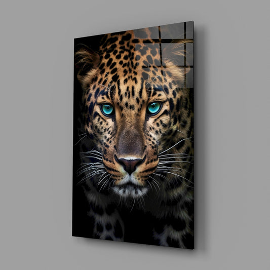 Glass wall art panel displaying a close-up leopard portrait with striking turquoise eyes against dark background, mounted at angle.