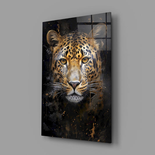 Angled view of a glass wall art panel featuring a leopard's face with golden eyes and black spots on dark background with gold splatter effects.