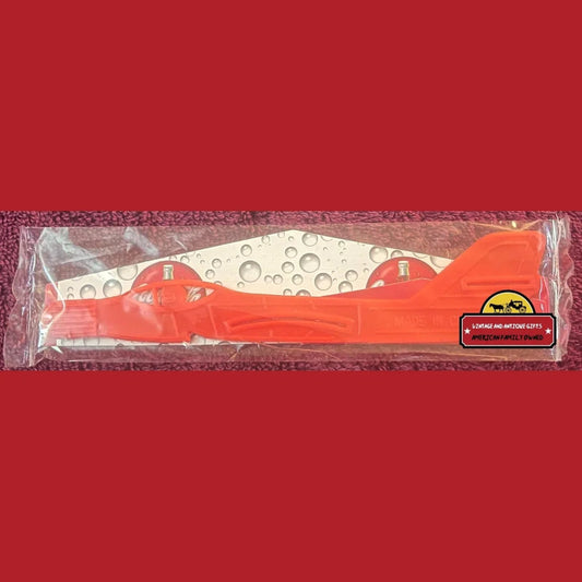 Orange plastic telephone handset in packaging for Y2K Coca-Cola Plane Glider