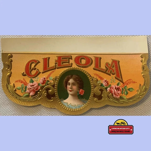 Antique Cleola cigar box label with a Victorian woman portrait, pink roses, and embossed gold scrollwork on an amber background