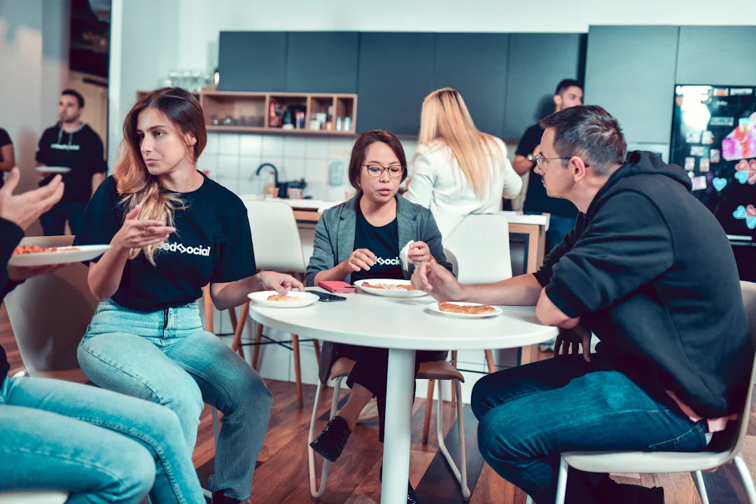 People chatting and eating around a white table to encourage customer reviews and leverage user-generated content