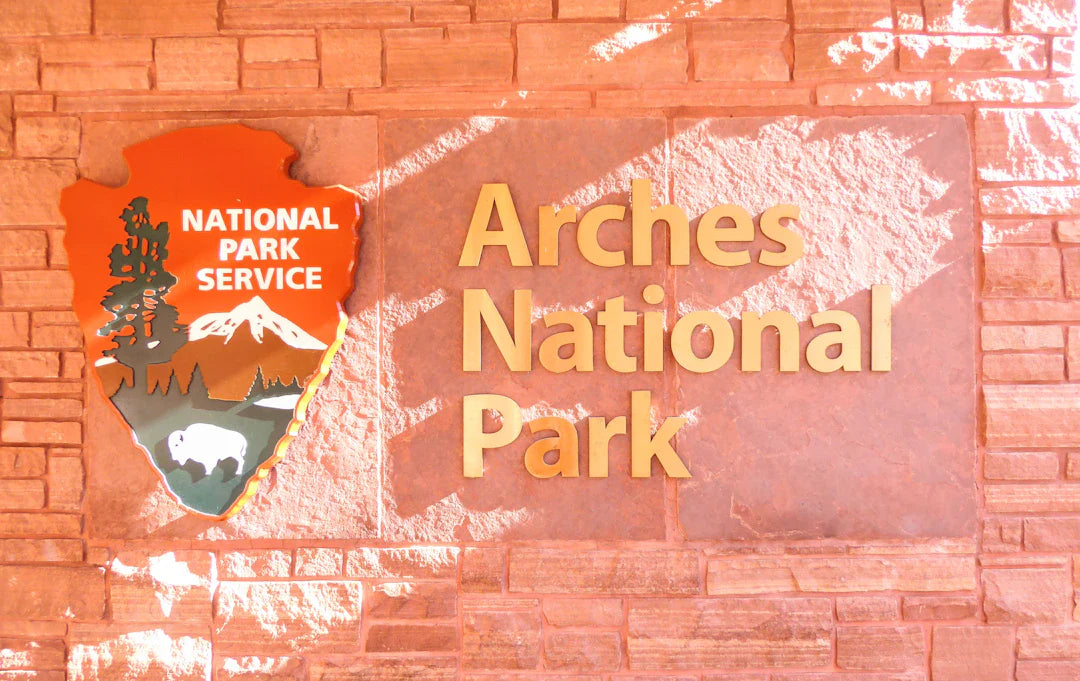 Orange brown wooden Arches National Park sign with NPS shield logo