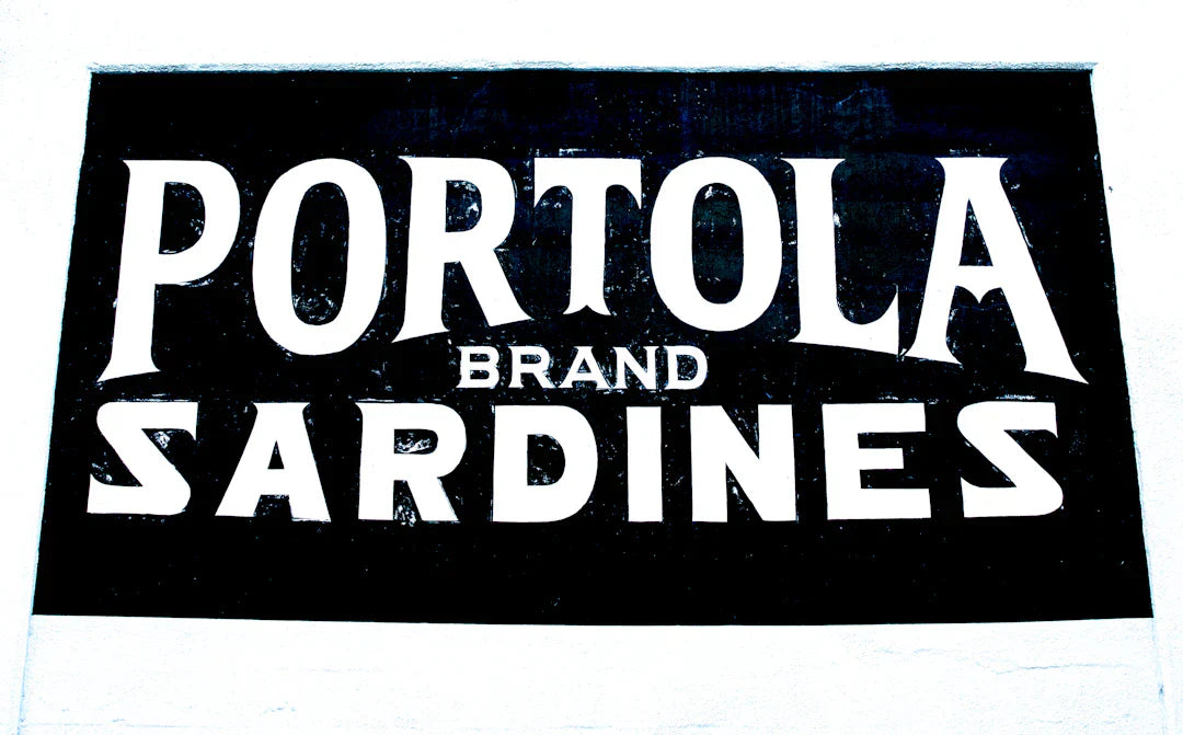 Vintage black and white Portola Brand Sardines sign showcasing classic vintage brand mascots