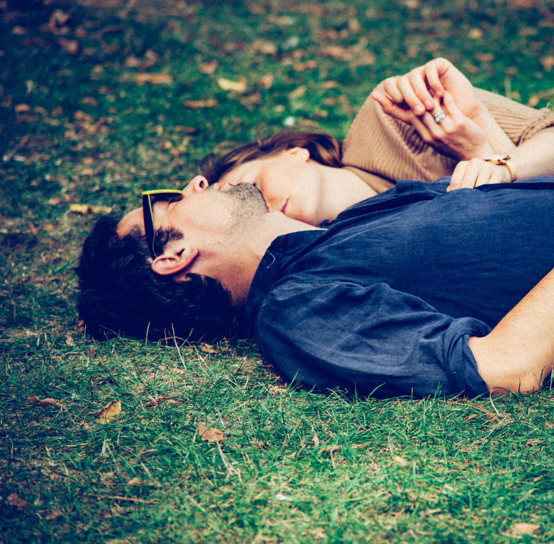 Couple lying on green grass inspired by famous love stories like Sarah Michelle Gellar and Jennifer Aniston