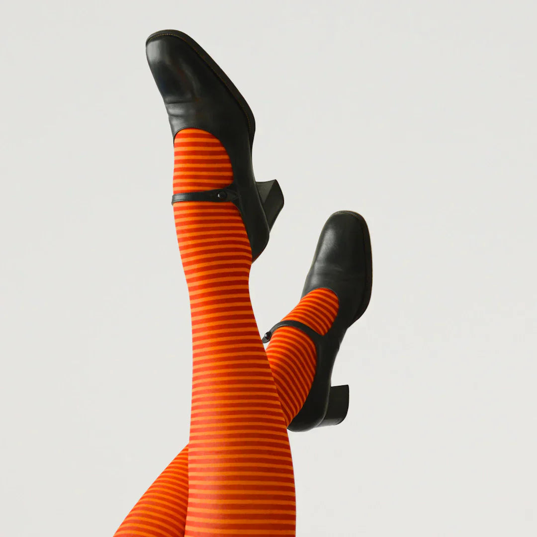 Orange striped tights with black Mary Jane shoes, iconic 90s fashion trend for crop tops