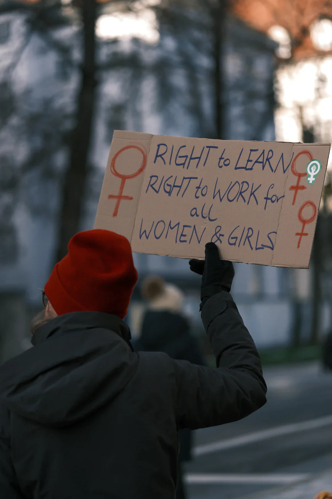 Person holding a cardboard sign advocating for workers rights in modern labor movements