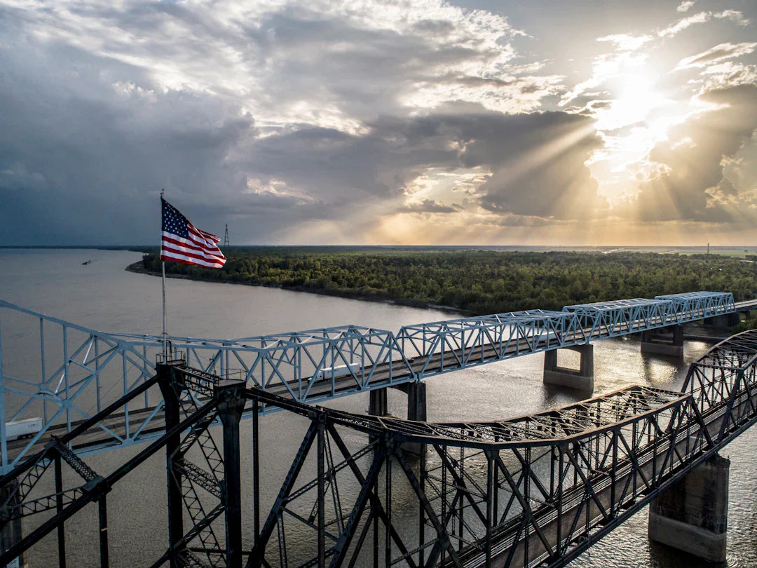 Steel bridge with US flag waving under blue skies, evoking Louisiana Purchase expansion
