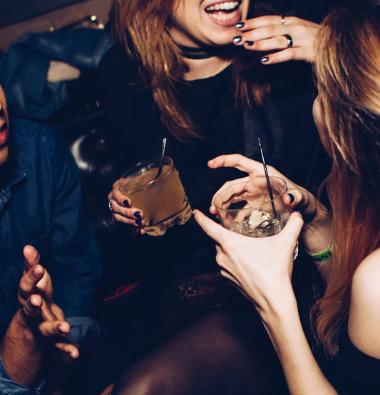 People holding drinks and reminiscing about 90s dance moves at a retro party