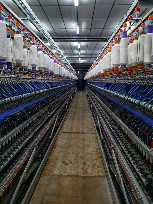 Long corridor of textile machinery with white thread spools in Northeast mills