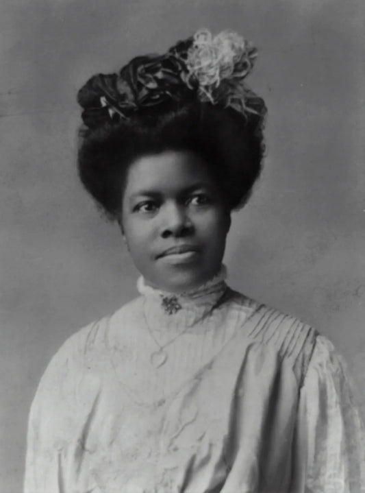 Black and white portrait of a wild west woman with a decorative hat and high-collared dress