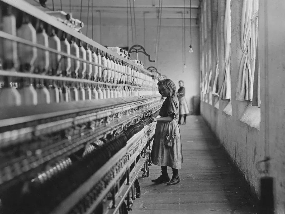Young child laborer at textile mill machine in Industrial America