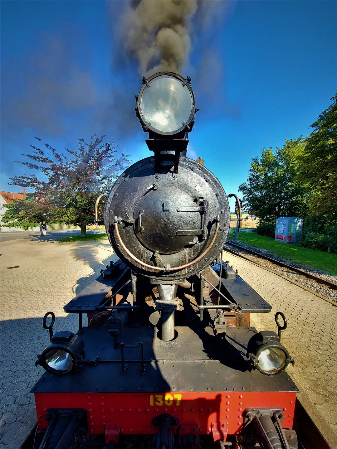 Black steam locomotive with headlight powering factory systems