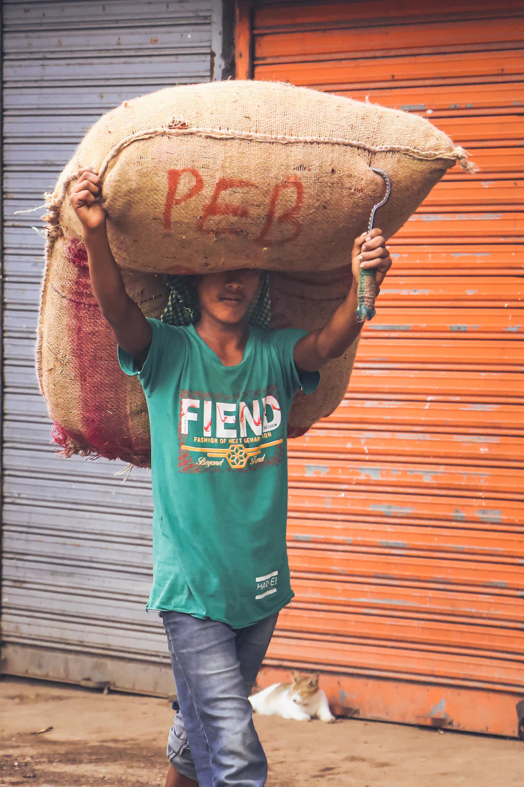 Person carrying large sack on head using hook, highlighting issues in child labor awareness