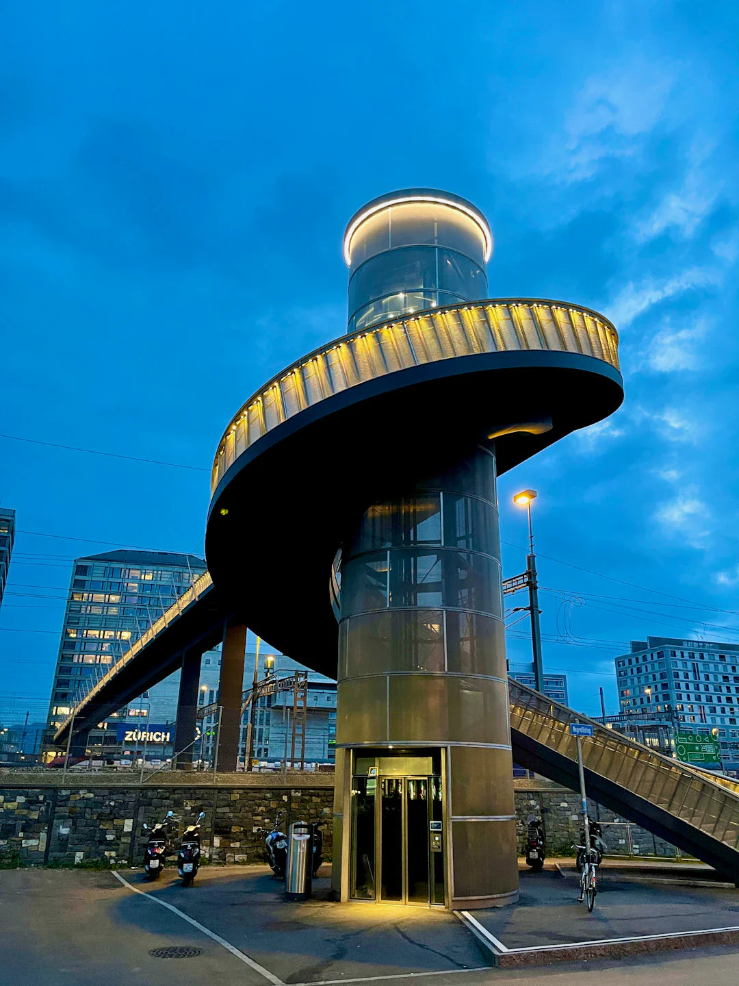 Modern pedestrian bridge with spiraling ramp and glass elevator tower in smart cities