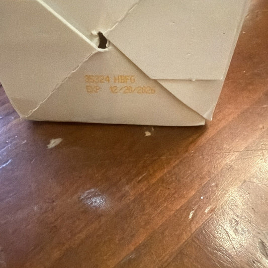 Cream-colored detox drink bottle lying on wooden floor, showing bottom with printed text and date 12/21/2025.