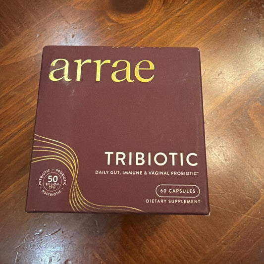 Burgundy box of Arrae Tribiotic probiotic capsules displayed on wooden floor, showing front packaging with gold text and decorative swirl design.