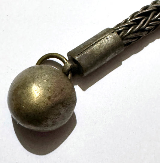 Vintage Chinese bronze pendant up close: the solid dome drop on its jump ring beside a rolled end cap, the cap's straight seam running its length