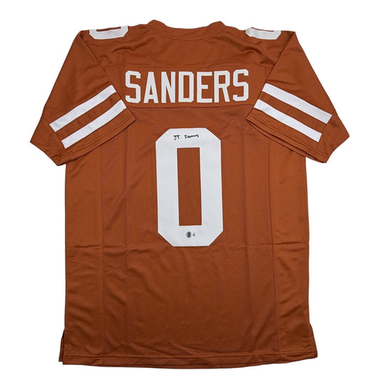 Flat lay of burnt orange college football jersey with white "SANDERS" name and "0" number, showing back view with white shoulder stripes and autograph.