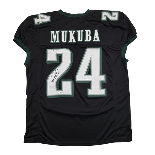 Back view of black pro cut football jersey with green trim displaying "MUKUBA" and number 24 with autographed signature.