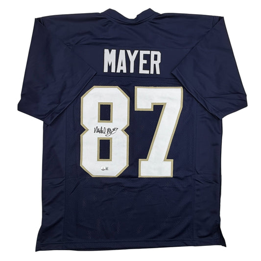Navy blue Notre Dame football jersey displaying "MAYER" and number "87" with white and gold trim, shown flat lay from back view.