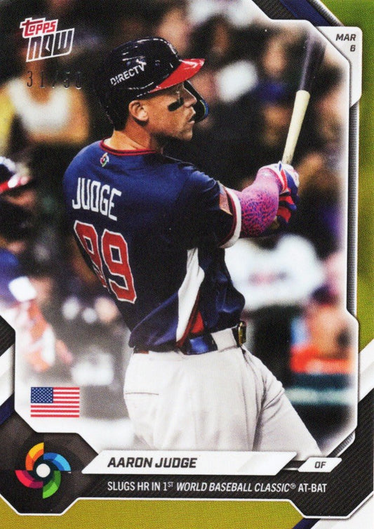 Aaron Judge in Team USA navy uniform mid-swing, wearing pink batting gloves and black cap with red visor, Topps Now baseball card.
