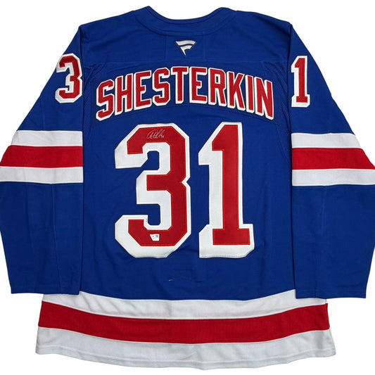 Back view of blue New York Rangers hockey jersey number 31 with "SHESTERKIN" nameplate and autograph, red and white stripes on sleeves and hem.