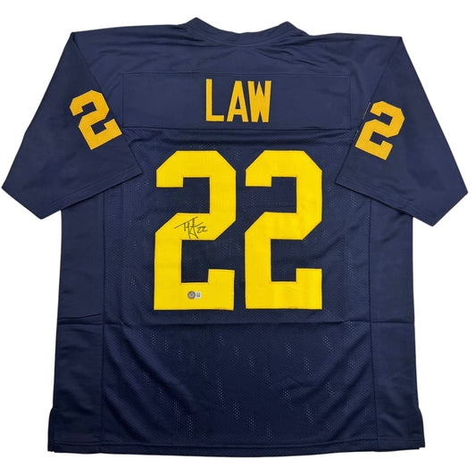 Back view of navy blue Michigan football jersey number 22 with yellow "LAW" nameplate and autographed number.