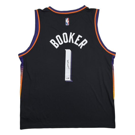 Back view of black Suns basketball jersey with "BOOKER" and number 1 in white lettering, navy and orange trim.