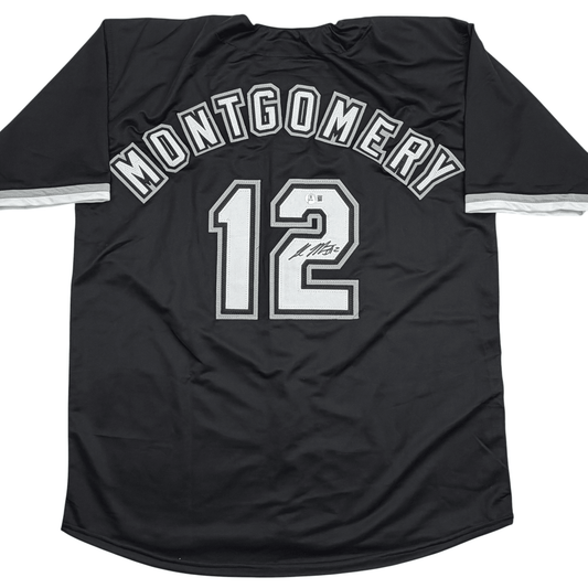 Back view of black baseball jersey with "MONTGOMERY" arched across shoulders, number "12" below, white stripe on sleeves, autographed.