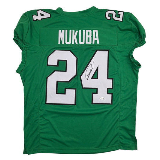 Back view of green pro cut football jersey displaying "MUKUBA" nameplate and white number 24 with autograph.