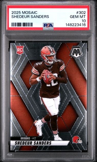 PSA-graded trading card in clear plastic case displaying Shedeur Sanders in brown Cleveland Browns uniform against red and black geometric background.