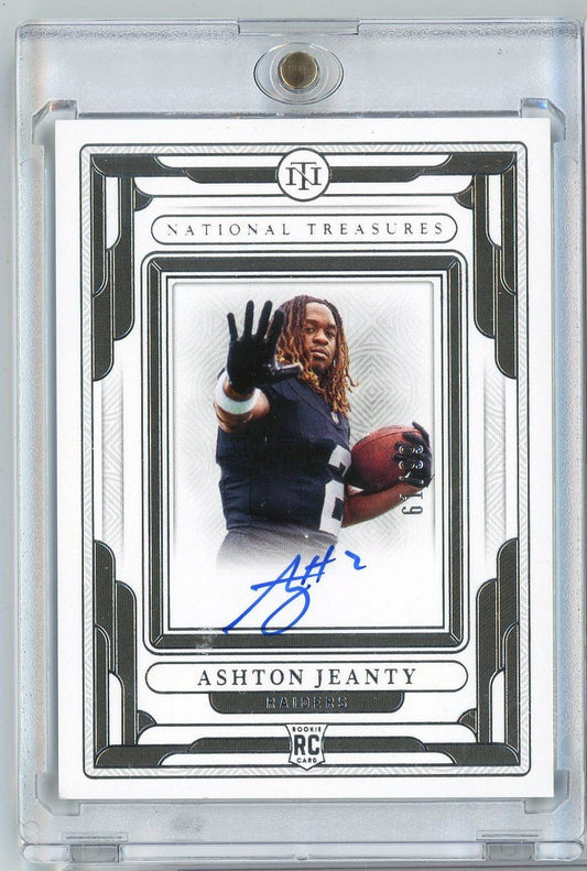 Signed rookie football card in clear plastic case showing Ashton Jeanty in Raiders uniform holding football, with blue autograph and ornate black-and-white border design.