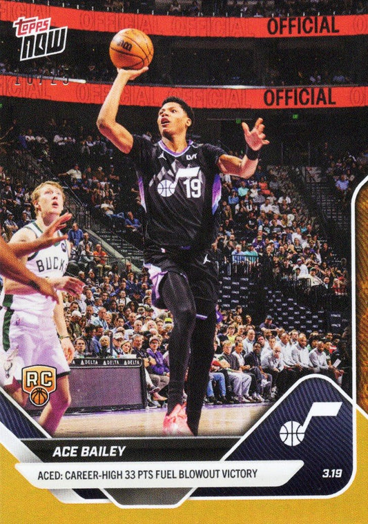 Ace Bailey in black Utah Jazz uniform shooting basketball over defender in pink Bucks jersey during game, Topps Now card with orange foil border and RC logo.