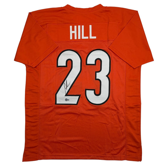 Back view of orange Cincinnati football jersey number 23 with "HILL" nameplate and player autograph on white numerals.