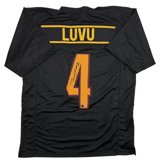 Back view of black football jersey with gold "LUVU" nameplate and orange number 4 with signature.