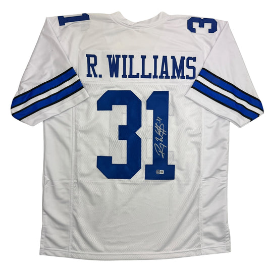 White Dallas Cowboys football jersey with blue "R. WILLIAMS" nameplate and number 31, displayed flat with autographed signature visible on the number.