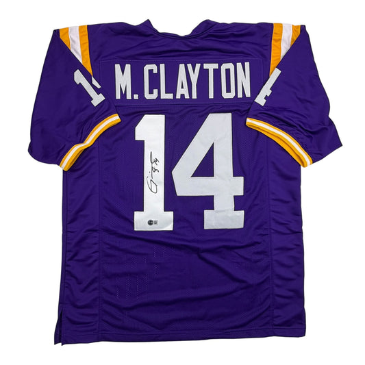 Purple LSU football jersey number 14 with M. Clayton nameplate and autographed signature, front view.