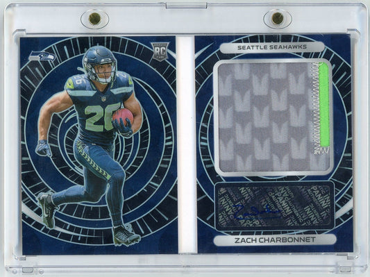 Two-panel rookie card showing front with Seahawks player number 29 running with football in blue uniform, and reverse with grey fabric swatch and player name Zach Charbonnet.