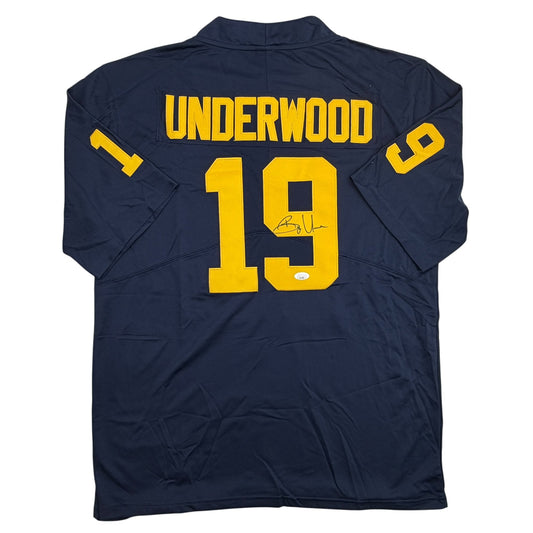 Back view of navy blue college football jersey with yellow "UNDERWOOD" text and number "19" across shoulders, featuring an autograph on the chest.